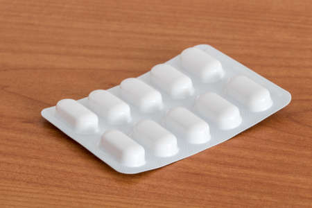 Ten tablets in blister pack on wooden table.