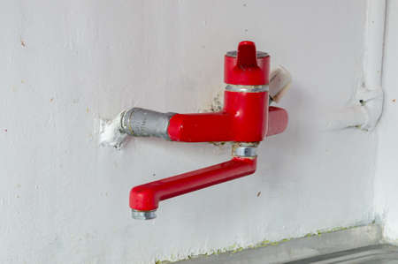 Red faucet on the wall in kitchen. Old red water tap on the wall in the kitchen.