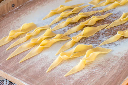Raw angel wings on wooden desk. Polish faworki traditional sweet crisp pastry made out of dough that has been shaped into thin twisted ribbons.の写真素材