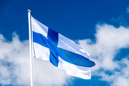 Finland national flag waving on blue sky. Flag of Finland also called Siniristilippu.の写真素材