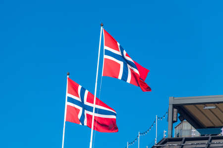 National flag and ensign of Kingdom of Norway on blue sky.の写真素材