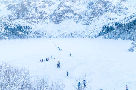Frozen Morskie Oko (Eye of the Sea) lake with people in winter in Tatra mountain, Poland.の写真素材