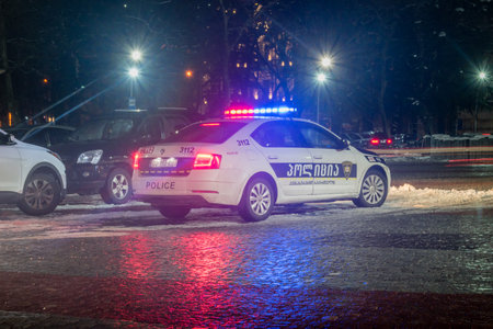 Kutaisi, Georgia - March 17, 2022: Georgian police car with turn on flashlights parked at central square of Kutaisi at night.のeditorial素材