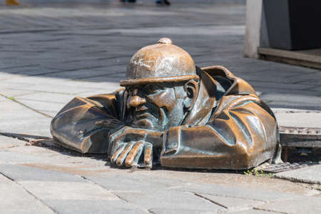 Bratislava, Slovakia - May 31, 2022: Street sculpture known as Cumil Man at Work. The sculpture shows a sewer man leaning out of an open manhole.のeditorial素材