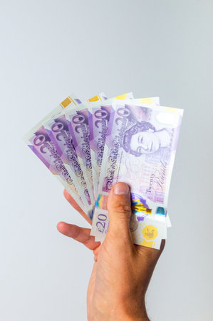 5 twenty pound sterling notes held in his right hand.