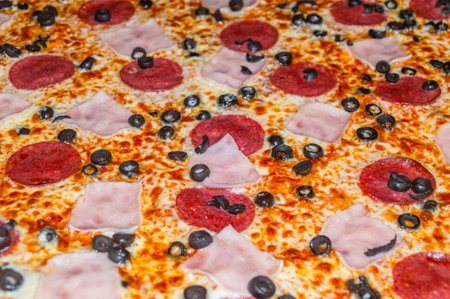 Close-up of pizza with ham, salami and black olives.の写真素材