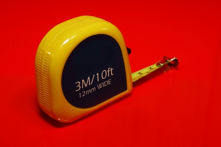 The yellow measure tape on the red background.の写真素材