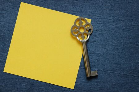 Yellow note with vintage key on dark backgroundの写真素材