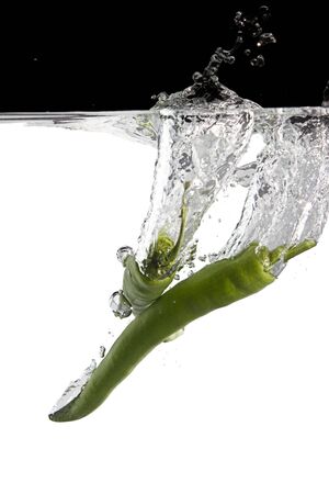 two green chilli thrown in water with black and white backgroundの写真素材