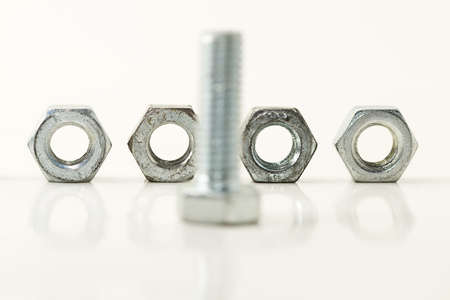 four screws standing behind one bolt on white background