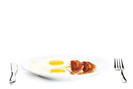 fried eggs and bacon on a plate on white backgroundの写真素材