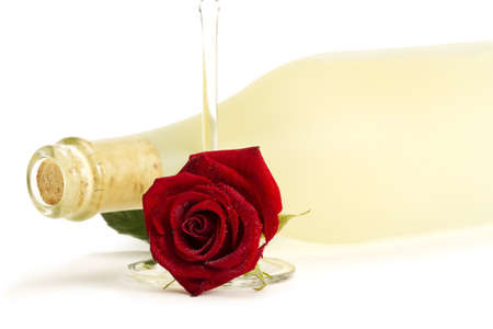 wet red rose with a empty champagne glass in front of a dull prosecco bottle on white backgroundの写真素材