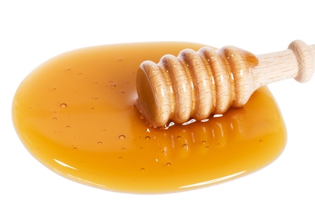 honey dipper from slightly top in a puddle of honey on white backgroundの写真素材