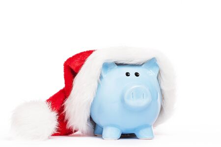 blue piggy bank wearing santas hat on white backgroundの写真素材