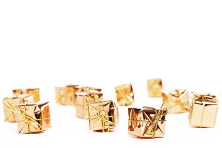 tiny golden christmas presents on white backgroundの写真素材