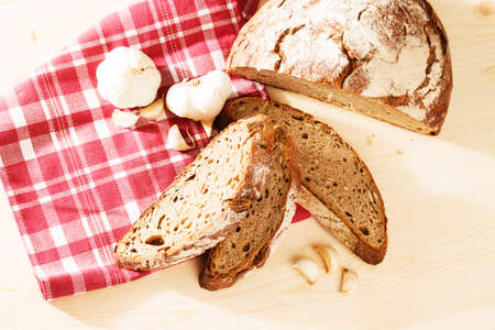 rustic rye bread from top with garlic on wooden background with a towelの写真素材