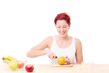 happy woman at breakfast cutting a orange on white backgroundの写真素材