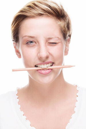 blonde happy woman winking with pencil in her mouth on white backgroundの写真素材