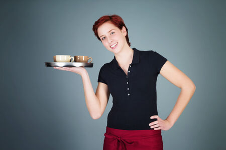 young happy redhead waitress serving coffee with a trayの写真素材