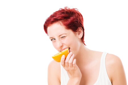 winking woman bites in a orange on white backgroundの写真素材