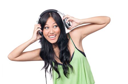 A young Asian girl looking excited putting on a pair of headphones.の写真素材