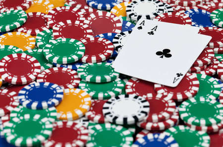 A pair of black aces set on top a large pile of poker chips.