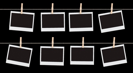 Two rows of four blank pieces of instant film held on strings with  clothespins isolated on black.の写真素材