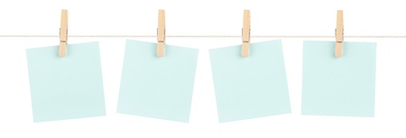 A set of four blank blue sticky notes held on a string with clothespins isolated on white.の写真素材