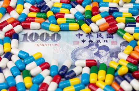 A one thousand NT dollar bill covered with colorful pills with focus on the number 1000.