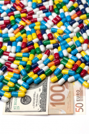 American, Canadian and European currency covered by pills isolated on a white background.の写真素材