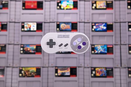 Taipei, Taiwan - June 19, 2019: A Super Nintendo  controller floating over a pile of SNES game cartridgesのeditorial素材