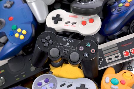 Taipei, Taiwan - May 1, 2019: A black Playstation controller on top of a large pile of video game controllersのeditorial素材