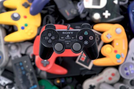 Taipei, Taiwan - May 1, 2019: A black Playstation controller floating over a large pile of video game controllersのeditorial素材