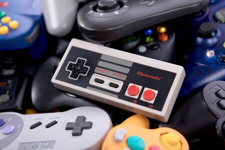 Taipei, Taiwan - May 1, 2019: A NES controller on top of a large pile of video game controllers