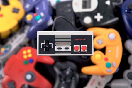 Taipei, Taiwan - May 1, 2019: A Nintendo NES controller floating over a large pile of video game controllersのeditorial素材