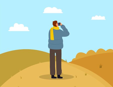 Man photographing picturesque view. Male wearing casual clothes and scarf standing on grass and making photo. Back view of person photographer holding shooting landscape of autumn park vectorのイラスト素材
