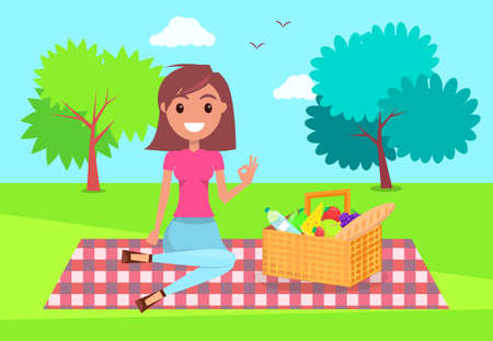 Young girl sitting at checkered plaid in park with basket full of products. Smiling girl relaxing at nature, summer time. Pretty female wearing t-shirt, jeans resting at picnic. Girl show ok signのイラスト素材