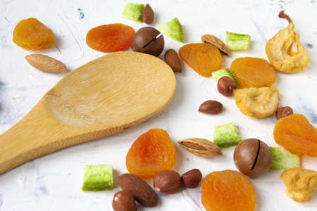 Dried fruits and nuts, apricot, almond, hazelnut, pear, prune and macadamia with bamboo wooden spoon on white background. High quality photoの写真素材