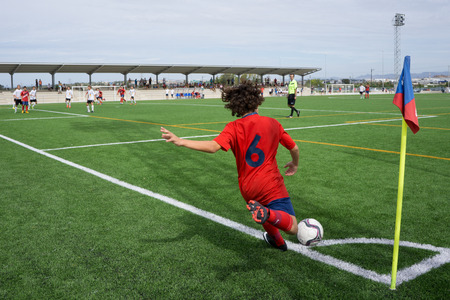VALENCIA, SPAIN - SEPTEMBER 20, 2014: An unknown youth player taking a corner kick during a youth soccer match.のeditorial素材