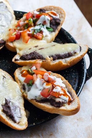 Molletes. Vegetarian Mexican food similar to bruschetta. Refried beans and melted cheese on toasted bread.の写真素材