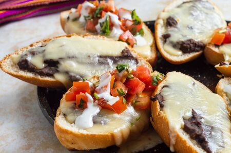 Molletes. Vegetarian Mexican food similar to bruschetta. Refried beans and melted cheese on toasted bread.の写真素材