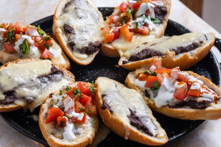 Molletes. Vegetarian Mexican food similar to bruschetta. Refried beans and melted cheese on toasted bread.の写真素材