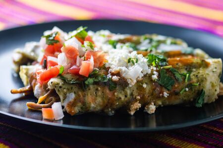Enchiladas Verdes, or green enchiladas, tortillas filled with chicken and topped with green sauce, cheese and creamの写真素材