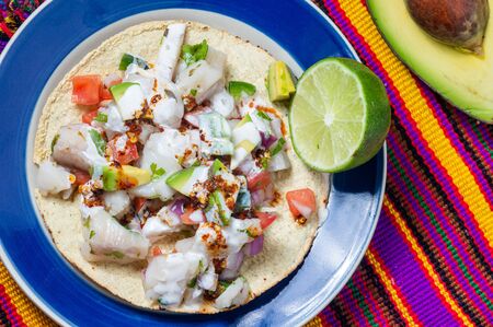 Fish ceviche, Mexican food from Peruvian origin. Raw fish marinated in lime juice with raw onion, tomato, jalapeno pepper, avocado and herbs. Served on crispy fried tortillas.の写真素材