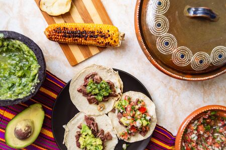 Mexican carne asada tacos, literally grilled meat tacos. These are chopped barbecued beef served on soft corn totillas with salsa verde and pico de galloの写真素材