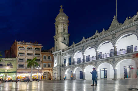 VERACRUZ, MEXICO 20 JUNE 2018: Evening in the colonial center of the city of Veracruz. A woman on mobile phone in front of the municipal building and Colonial hotelのeditorial素材