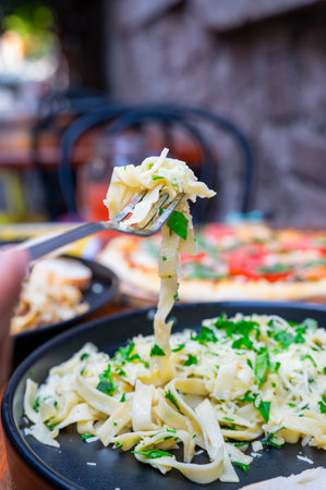 Cacio E Pepe, Traditional Italian Dish with Fork Holding Pasta in Front of Pizzaの写真素材