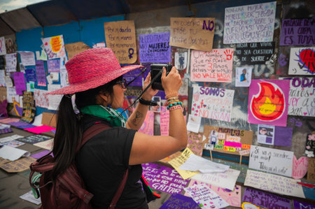 MEXICO CITY, MEXICO - MARCH 8, 2026: Young woman photographs protest signs in Mexico Citys main square. 8M march 2026のeditorial素材