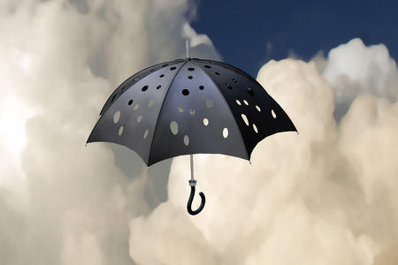 3d illustration flying pierced umbrella over storming sky backgroundの写真素材
