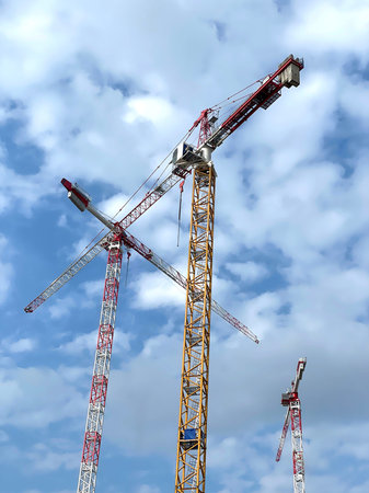 Tower cranes against blue sky with clouds. Industrial background.